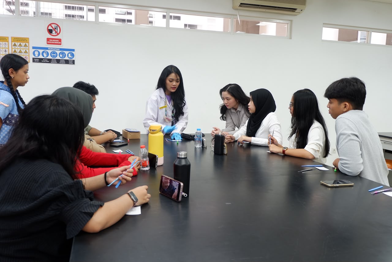 Mahasiswa berjas lab memandu satu kelompok peserta di meja skills lab